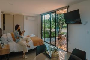 a woman sitting on a bed looking at her cell phone at Lodwine Lodge Apartments in Ciudad Lujan de Cuyo