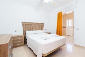 a bedroom with a white bed and a wooden dresser at Chalet del Lago in Torrevieja +12 photos