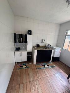 a kitchen with white walls and a wooden floor at Família Ebeneze in Santa Maria Madalena