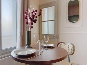 a table with wine glasses and a vase with flowers at Le Studio du Chateau in Bréviandes