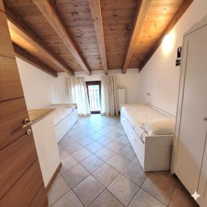 a room with two beds and a wooden ceiling at L'Antico Fienile Mountain Lake Iseo Hospitality in Fonteno