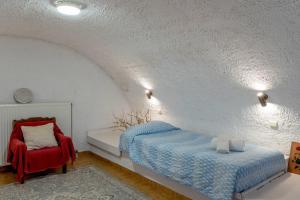 a bedroom with a bed and a red chair at Traditional House in Velies in Áyios Sarándos