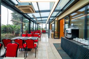 a restaurant with red chairs and tables and windows at Hotel Tiffany Milano in Trezzano sul Naviglio