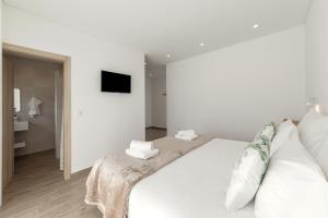 a white bedroom with a large bed with white pillows at Terra - B&P Infinity House in São Martinho do Porto +25 photos
