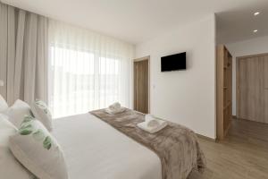 a bedroom with a large white bed with towels on it at Terra - B&P Infinity House in São Martinho do Porto