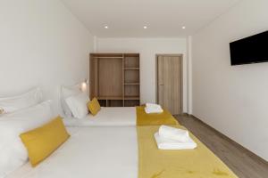 a bedroom with two beds and a flat screen tv at Terra - B&P Infinity House in São Martinho do Porto