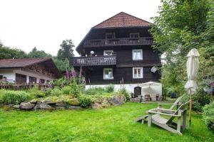 a large wooden house with a garden and an umbrella at Landhaus Dachsberg in Wittenschwand
