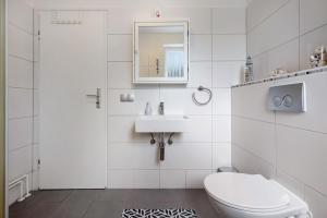 a white bathroom with a toilet and a sink at Ferienhaus Heide in Bad Fallingbostel +16 photos