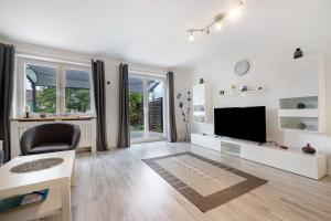 a white living room with a television and a chair at Ferienhaus Heide in Bad Fallingbostel