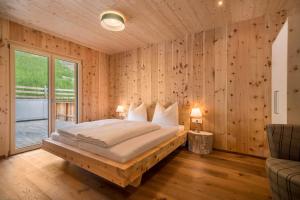 a bedroom with a large bed with wooden walls at Naturapartments Alpreid Zirbe in San Pancrazio dʼUltimo