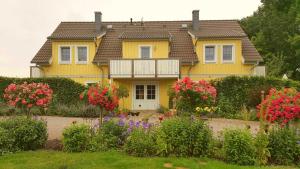 a yellow house with flowers in front of it at Ferienwohnung Heuschober in Neuendorf am See