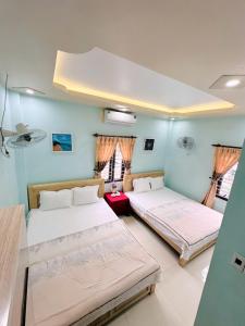 two beds in a room with blue walls and windows at Sơn Tùng Hostel in Cat Ba