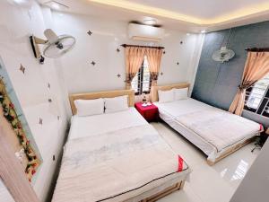 two beds in a room with two windows at Sơn Tùng Hostel in Cat Ba