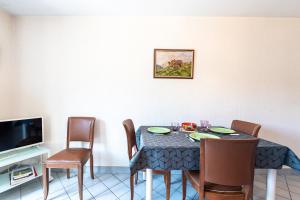 a dining room with a table with chairs and a television at Résidence du parc in Thônes