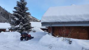 a red atv parked in the snow next to a house at Chalet Du Saix - Sauna in La Chapelle-dʼAbondance