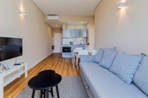 a living room with a blue couch and a kitchen at Setubal Prime, By Home Match in Setúbal