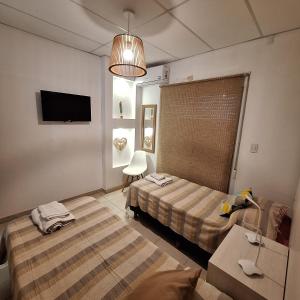a bedroom with two beds and a table and a tv at C1 Suite in Las Varillas