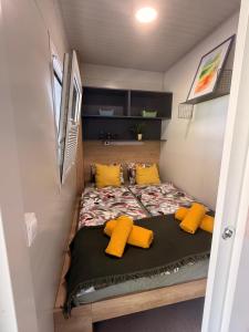 a bed in a tiny house with yellow pillows at Hiška Radolca - Camping Radovljica in Radovljica +22 photos