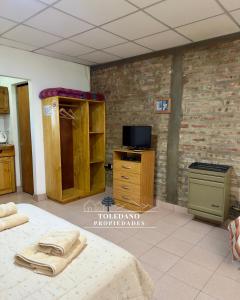 a room with a bed and a tv and a brick wall at Costa Azul 3 in Villa Pehuenia +4 photos