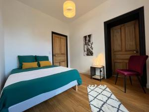 a bedroom with a bed and a chair and a door at L'aristide in Épinal