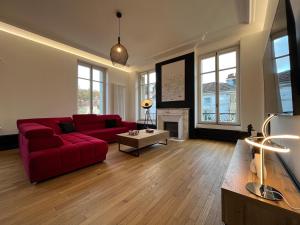 a living room with a red couch and a fireplace at L'aristide in Épinal