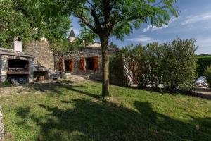 a stone house with a tree in the yard at Les Sources Gîte La Remise in Chambonas