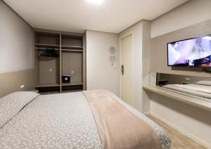 a bedroom with a bed and a flat screen tv at Hotel Palmas Executivo in Balneário Camboriú