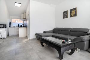 a living room with a black couch and a table at Neubau Ferienwohnung mit Balkon in Gronau +12 photos