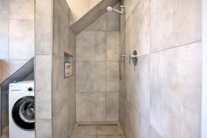 a shower stall in a bathroom with a washing machine at Neubau Ferienwohnung mit Balkon in Gronau