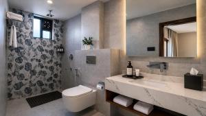 a bathroom with a toilet and a sink and a mirror at Valmere Chery Blossom Suites in Shillong +23 photos