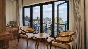 a room with a table and chairs and a large window at Valmere Chery Blossom Suites in Shillong