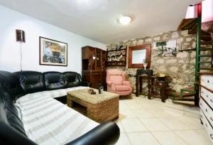 a living room with a black leather couch and a table at Robinson House with Pool & Seaview in Ždrelac