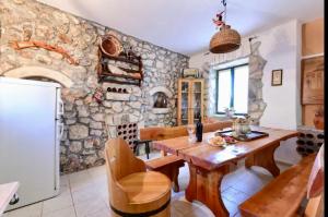 a kitchen with a wooden table and a stone wall at Robinson House with Pool & Seaview in Ždrelac