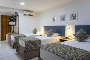 a hotel room with two beds and two chairs at Villa Park Hotel Fortaleza in Fortaleza