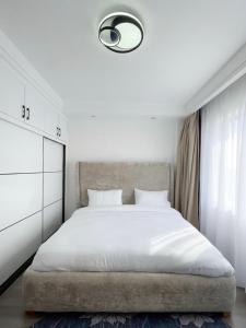 a bedroom with a large white bed and a window at Shangri-la residence Westlands-Remote working & gym in Nairobi