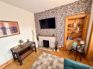 a living room with a fireplace and a tv on a brick wall at The Sandbed Retreat in Hawick