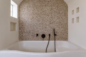 a bath tub in a room with a stone wall at Aeolos Villa Cleo in Agkidia +18 photos