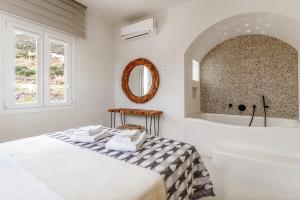 a white bedroom with a bed and a bath tub at Aeolos Villa Cleo in Agkidia