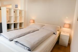a bed with white sheets and two lamps in a room at Ferienwohnung Malou in Tettnang