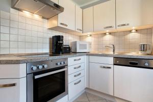 a kitchen with white cabinets and a stove top oven at Haus Janni in Freest