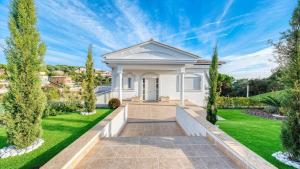 a white house with a lawn and trees at Costacabana - Villa Madison in Lloret de Mar