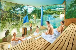 a group of people sitting on a deck in a pool at Ferienwohnungen Uhren Allgaier in Schönwald