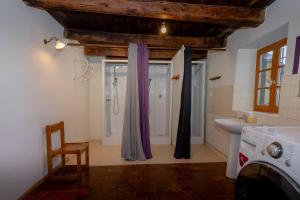 a bathroom with a sink and a shower with purple curtains at Le Palefroi De Merlas in Merlas