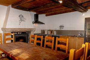 a kitchen with a wooden table and a fireplace at Le Palefroi De Merlas in Merlas