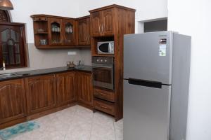 a kitchen with wooden cabinets and a white refrigerator at Villa Di Angelo Negombo in Negombo