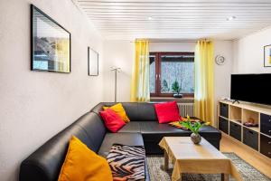 a living room with a black leather couch with colorful pillows at Ferienwohnung Waldeckchen in Waldeck