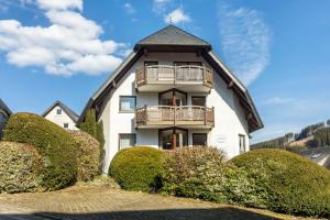 a large white building with a balcony and bushes at Appartmenthaus Felicitas in Willingen