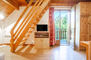 a living room with wooden stairs and a television at Appartement n°8 - 5 personnes in Saint-Sorlin-dʼArves