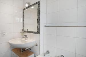 a white bathroom with a sink and a mirror at Geräumige schöne Ferienwohnung in Weingarten +15 photos