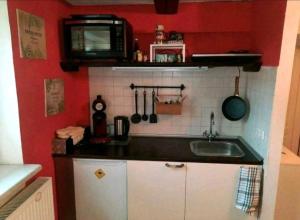 a small kitchen with a sink and red walls at Abendsonne in Wurster Nordseeküste
